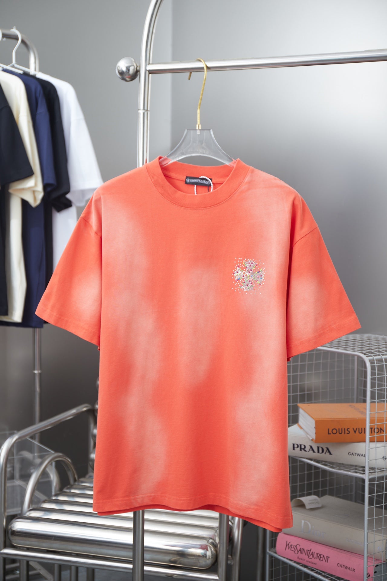 Coral orange short-sleeve crewneck T-shirt with small rhinestone floral emblem on chest