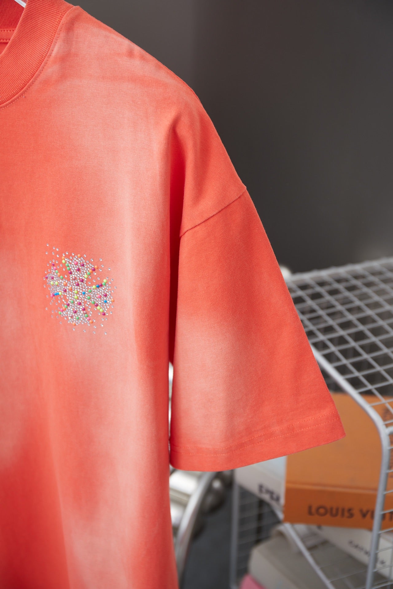 Coral orange short-sleeve T-shirt with rhinestone emblem detail on left chest