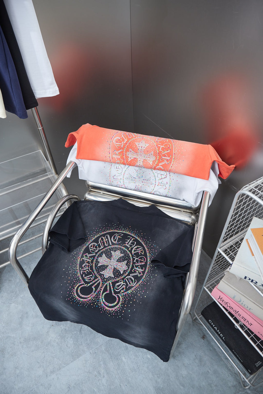 Folded shirts on a rack: orange, white, and black short-sleeve T-shirts