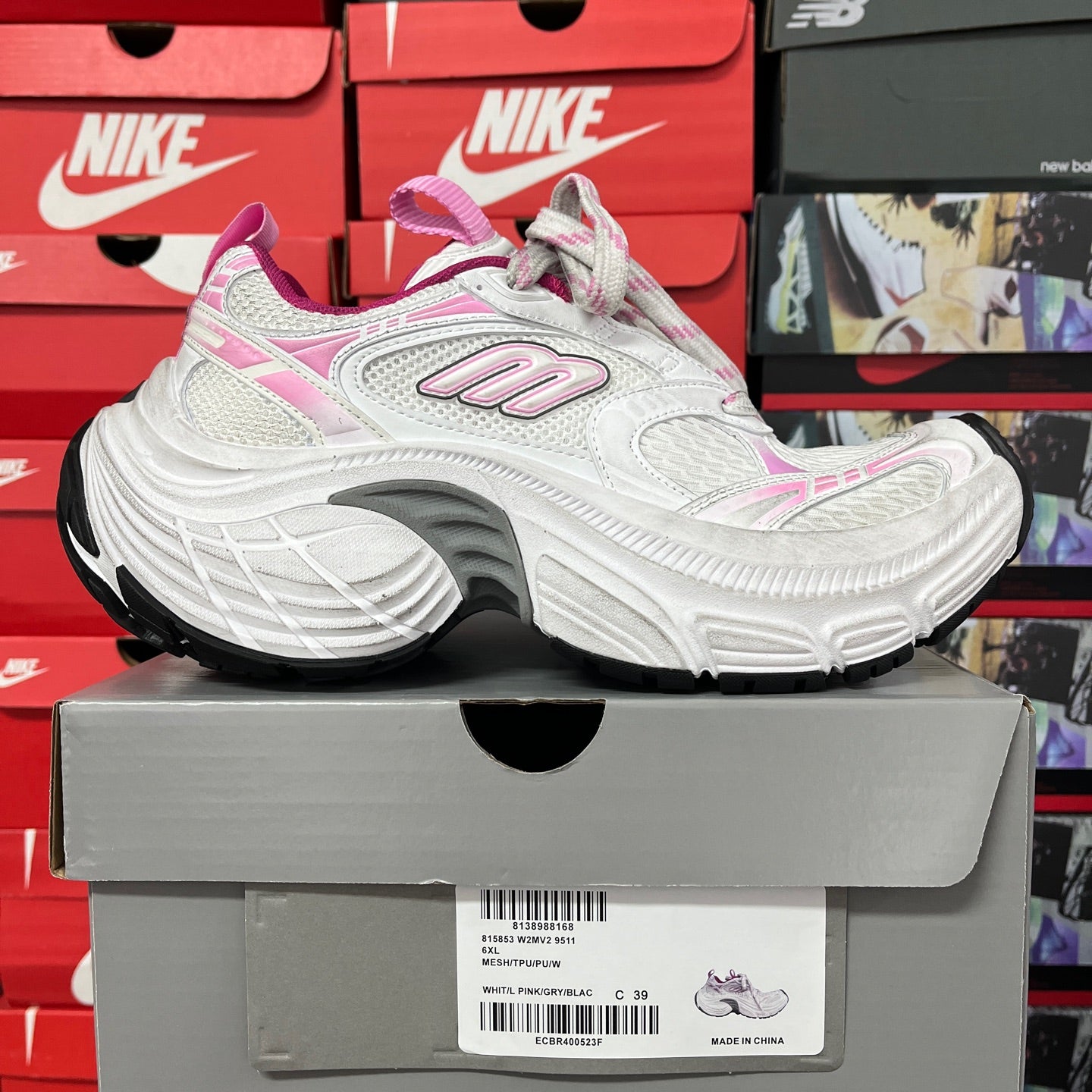 White and pink lace-up sneakers on a box, with side logo and thick padded sole
