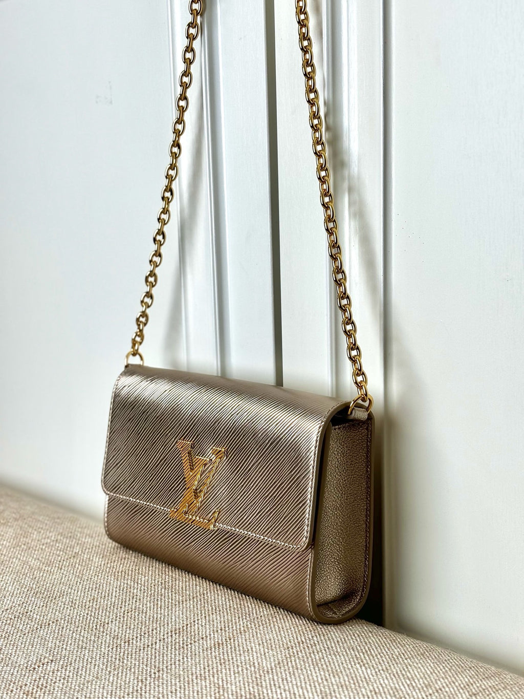 Small beige textured crossbody bag with LV-style logo and gold chain strap