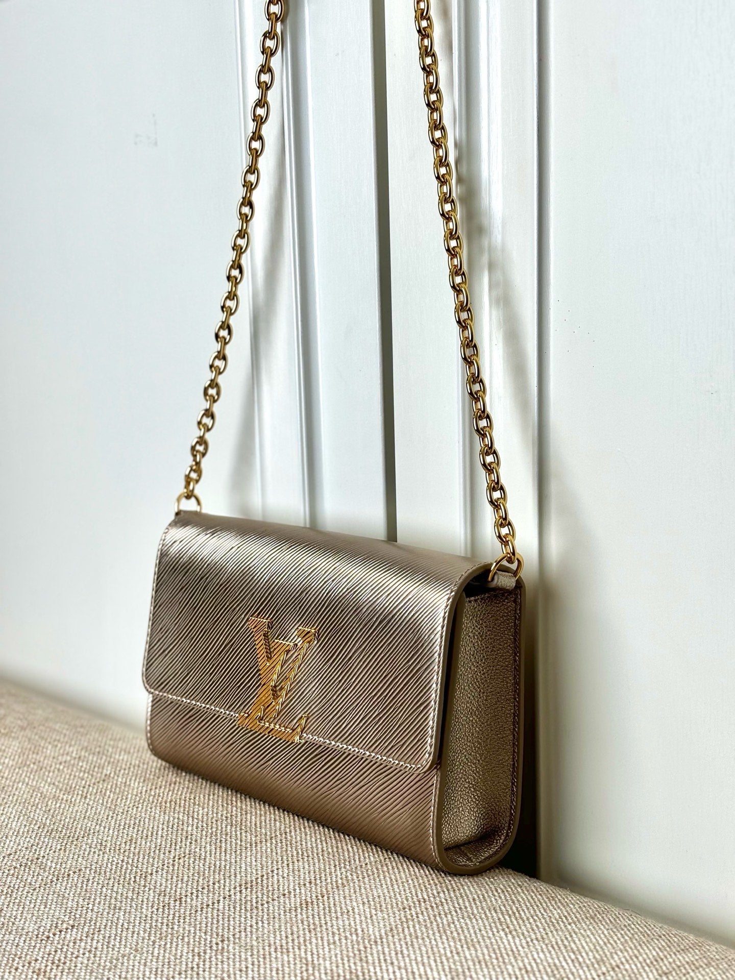 Small beige textured crossbody bag with LV-style logo and gold chain strap