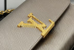 Close-up of gold LV-style logo on textured beige flap
