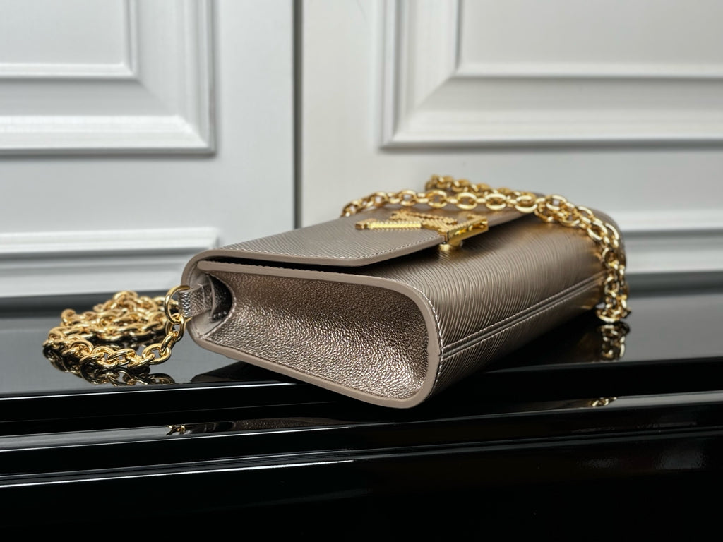 Beige textured clutch-style bag with gold chain strap and logo on flap