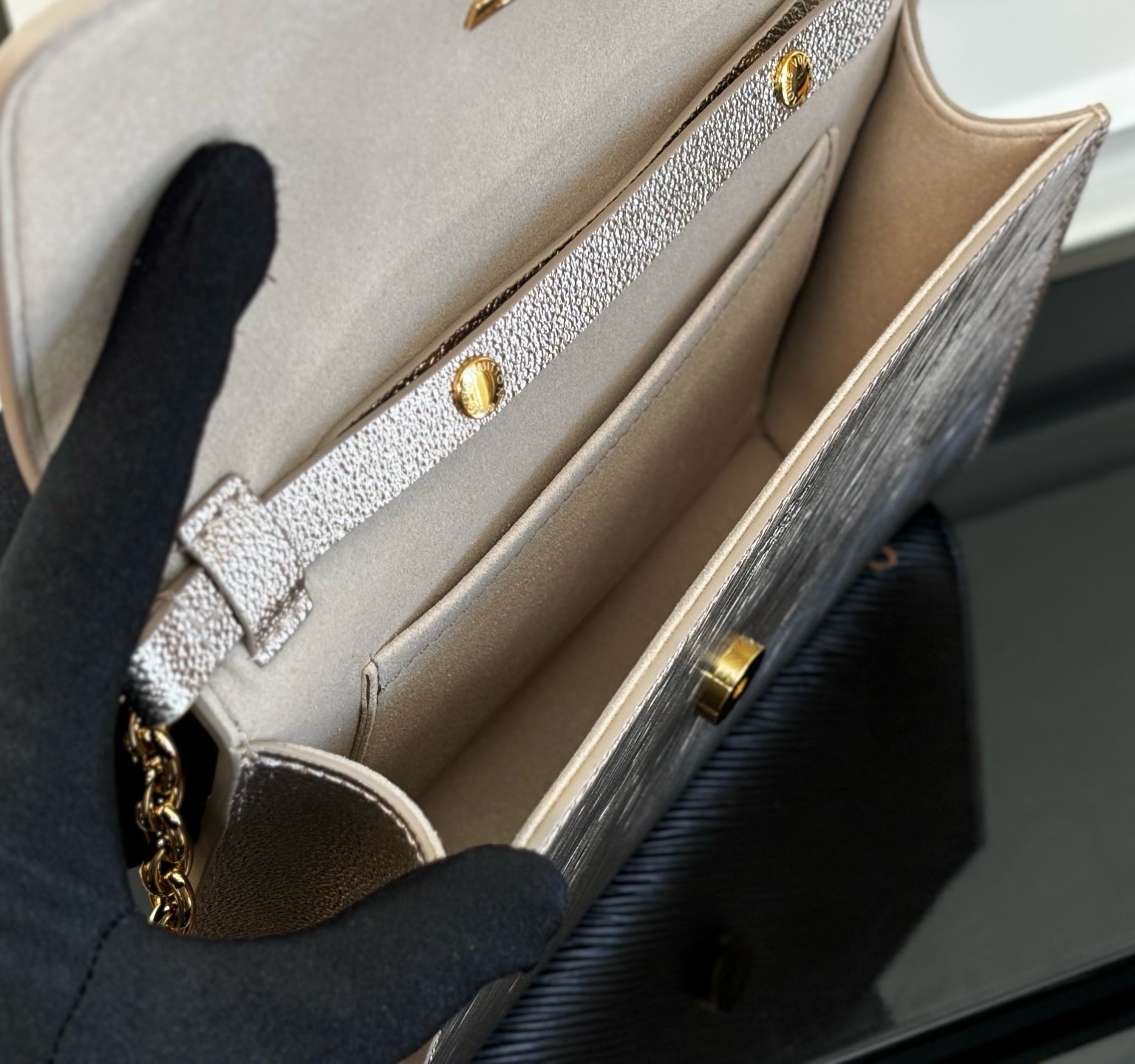 Beige interior compartment of a textured crossbody bag with gold snap hardware
