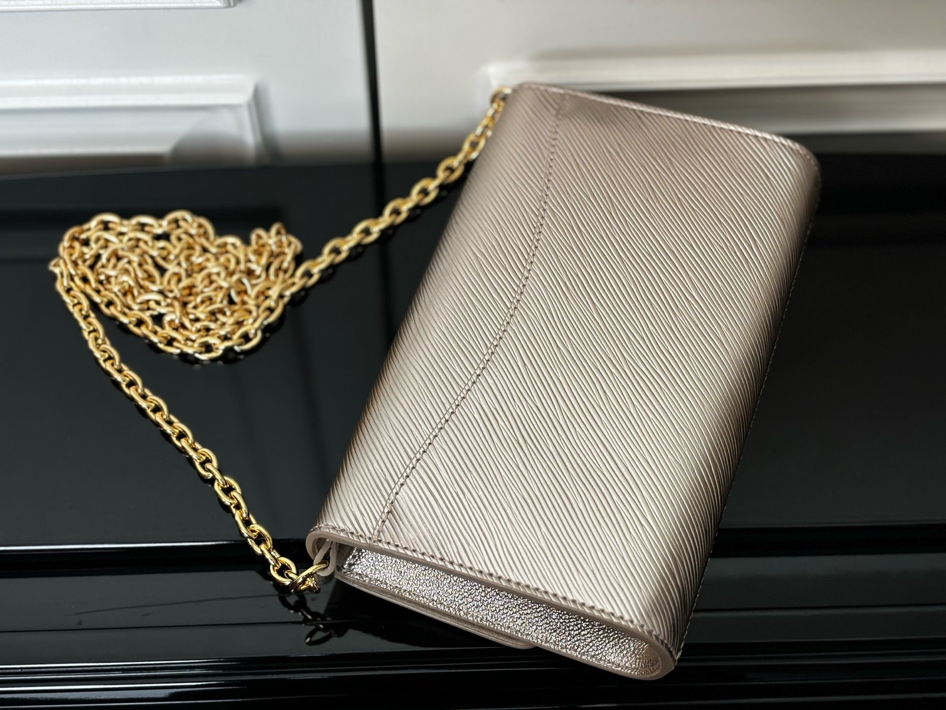 Beige textured crossbody bag with gold chain strap, flap logo detail