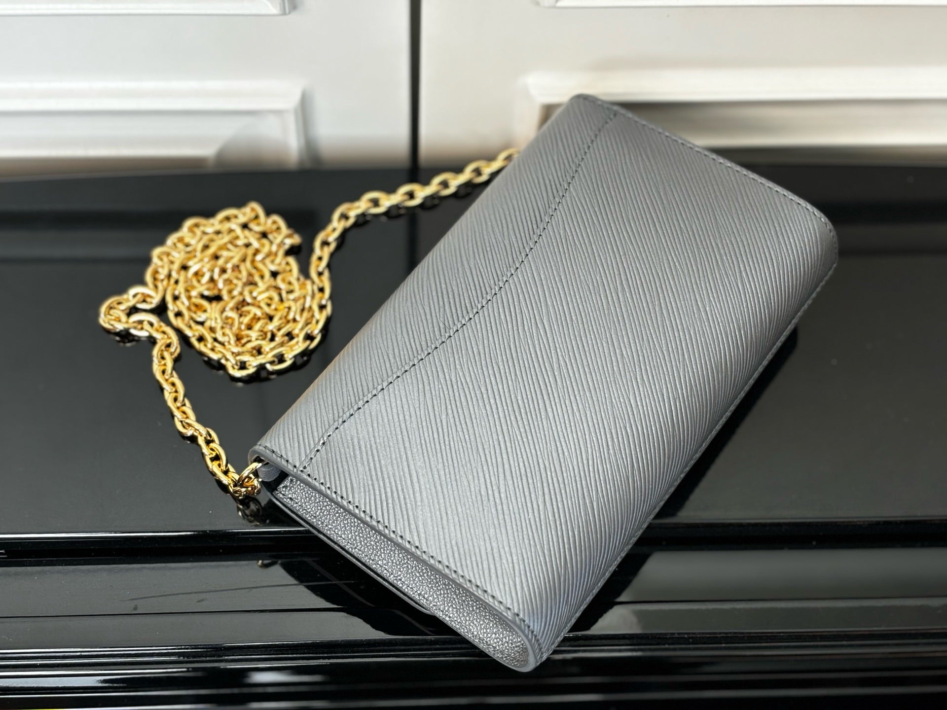 Louis Vuitton crossbody bag in light blue-gray with gold chain strap, angled view