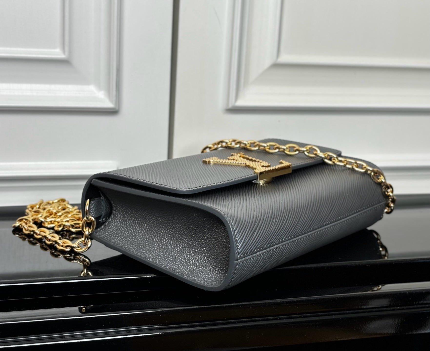 Louis Vuitton flap crossbody bag in light blue-gray, side view with gold chain strap
