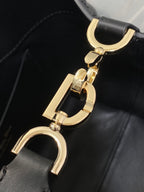 Dior gold-tone D-ring hardware and strap details on black leather bag