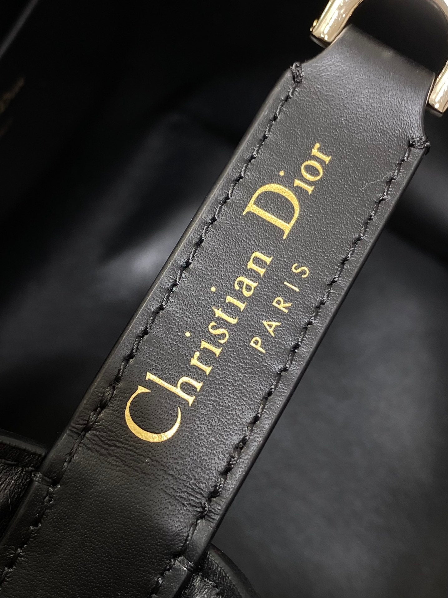 Dior 'Christian Dior Paris' text on black leather strap edge