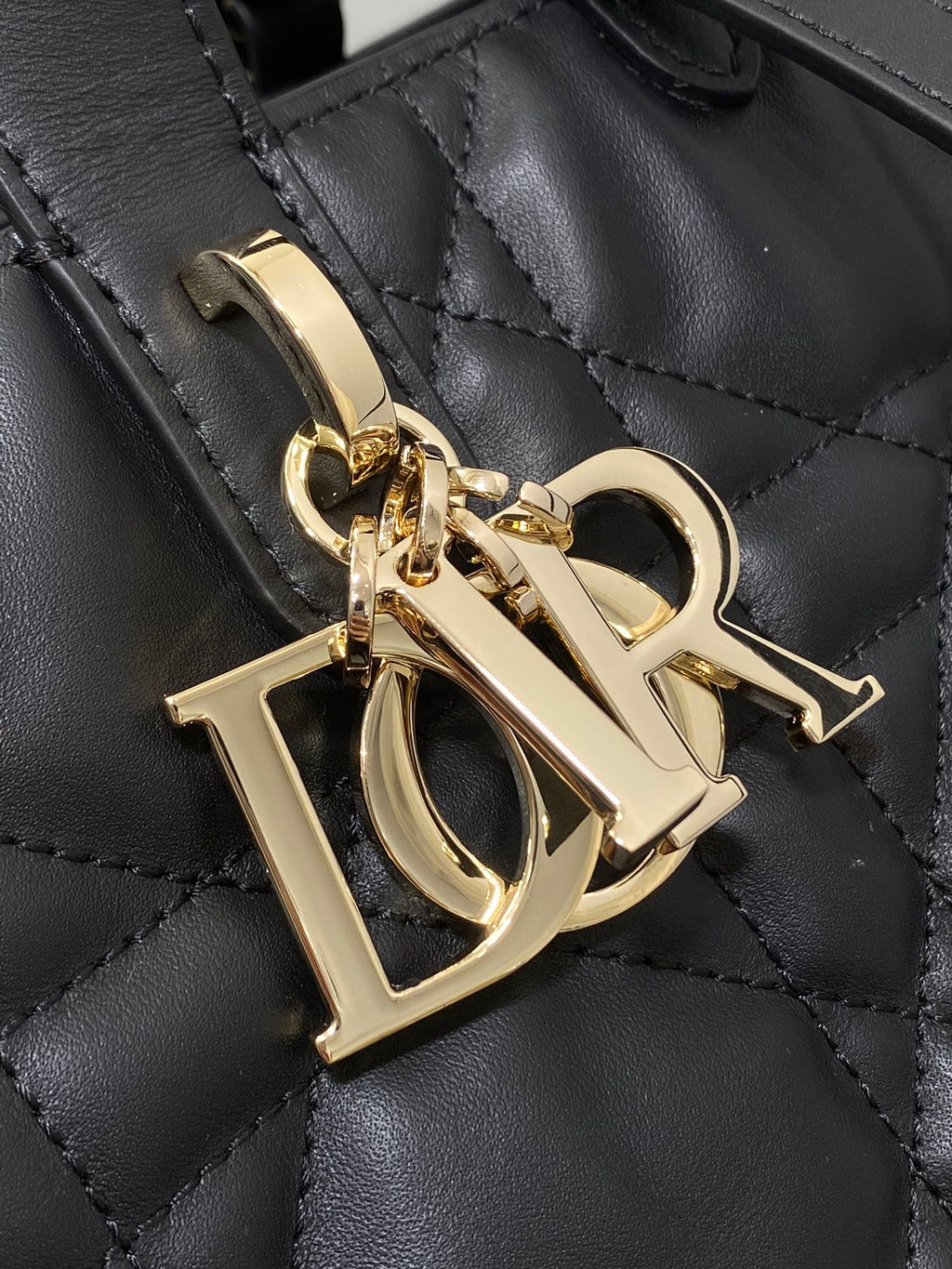 Dior gold-tone hardware charm on black quilted leather bag