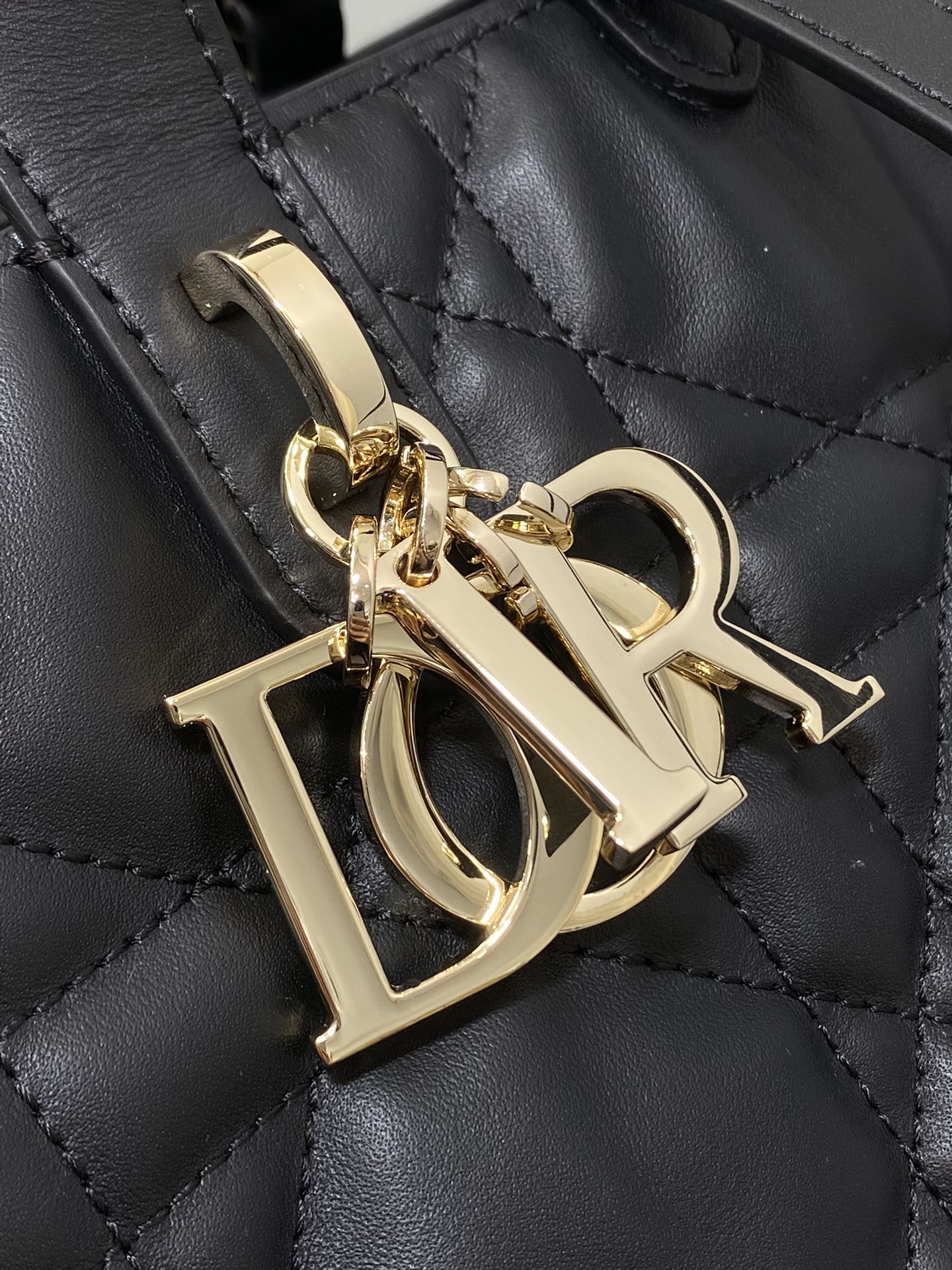 Dior gold-tone hardware charm on black quilted leather bag