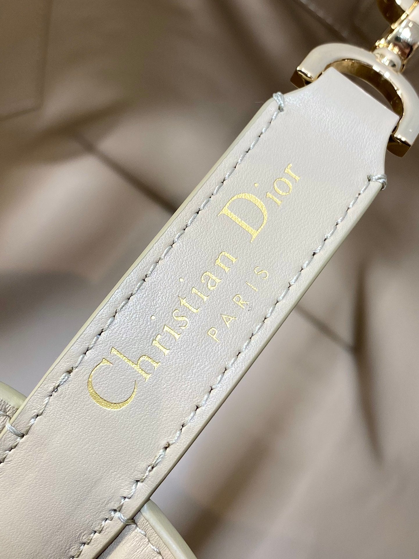 Dior cream leather label with “Christian Dior” text and stitched edge detail