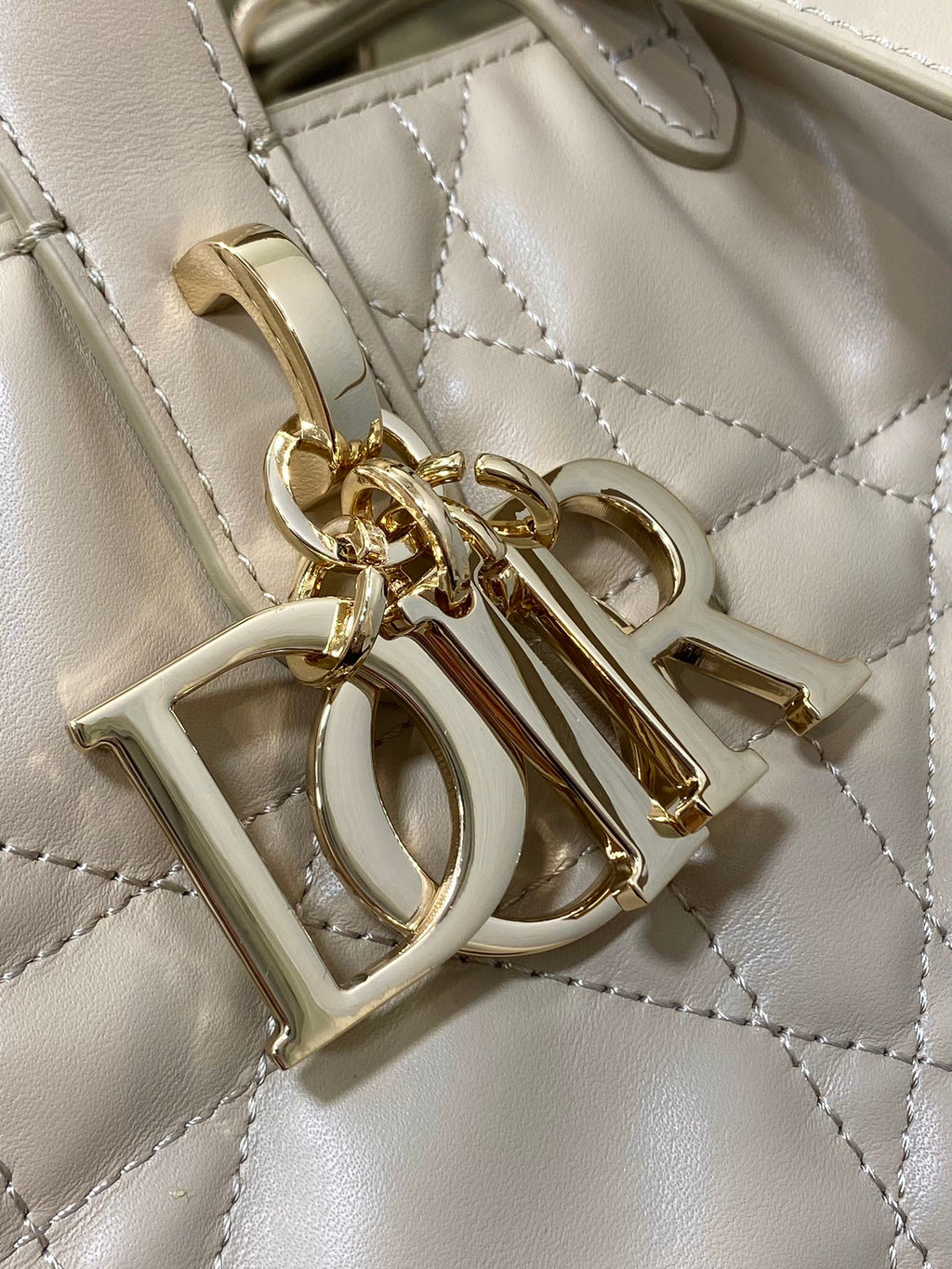 Dior cream handbag hardware and charm detail with gold-tone letters and rings