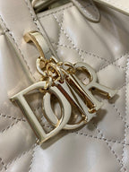 Dior cream handbag hardware and charm detail with gold-tone letters and rings