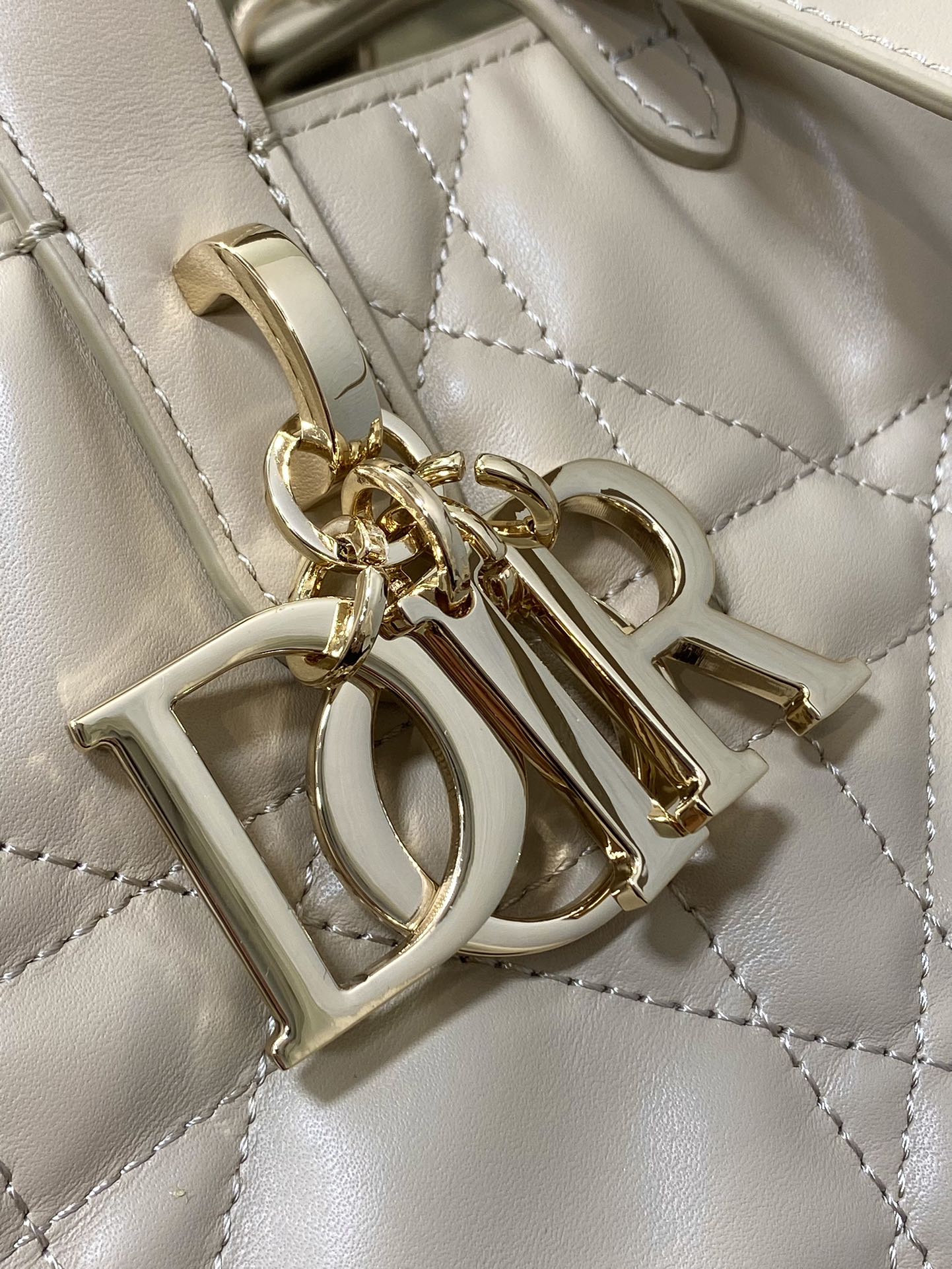 Dior cream handbag hardware and charm detail with gold-tone letters and rings