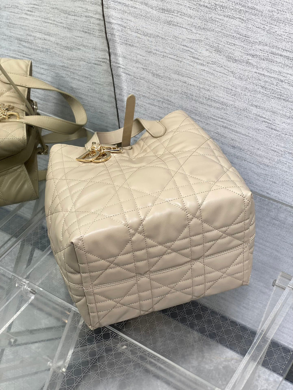 Dior cream quilted handbag top view with rope handle and gold-tone front charm