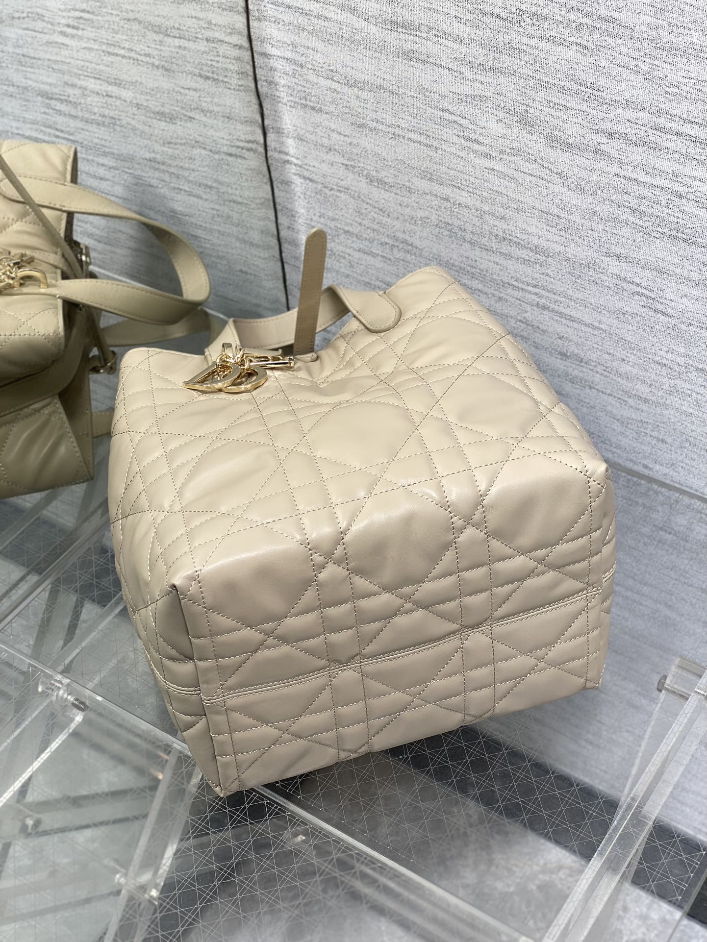 Dior cream quilted handbag top view with rope handle and gold-tone front charm