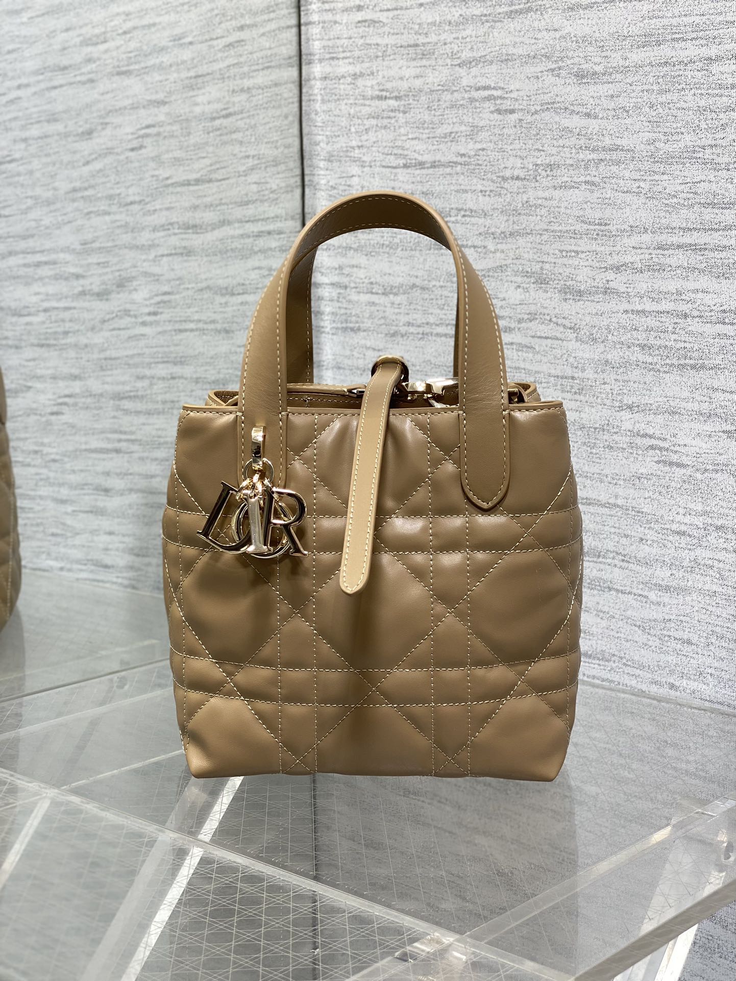 Dior quilted mini handbag in beige with top handles and gold-tone logo charm