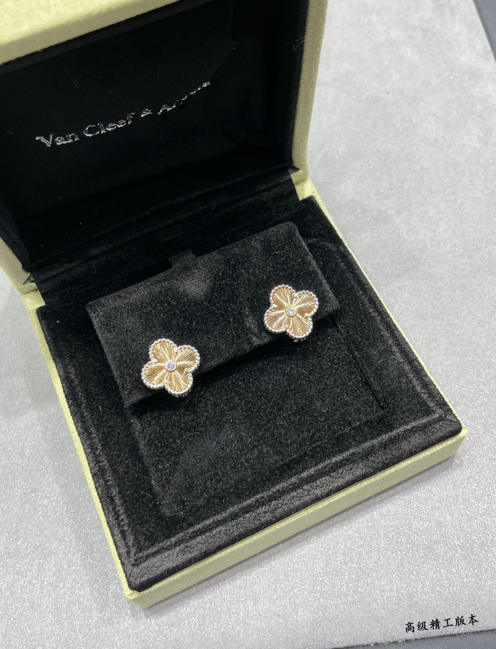 Gold-tone clover flower stud earrings, two in black jewelry box.