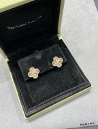 Gold-tone clover flower stud earrings, two in black jewelry box.