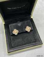 Gold-tone clover flower stud earrings centered in black display box.