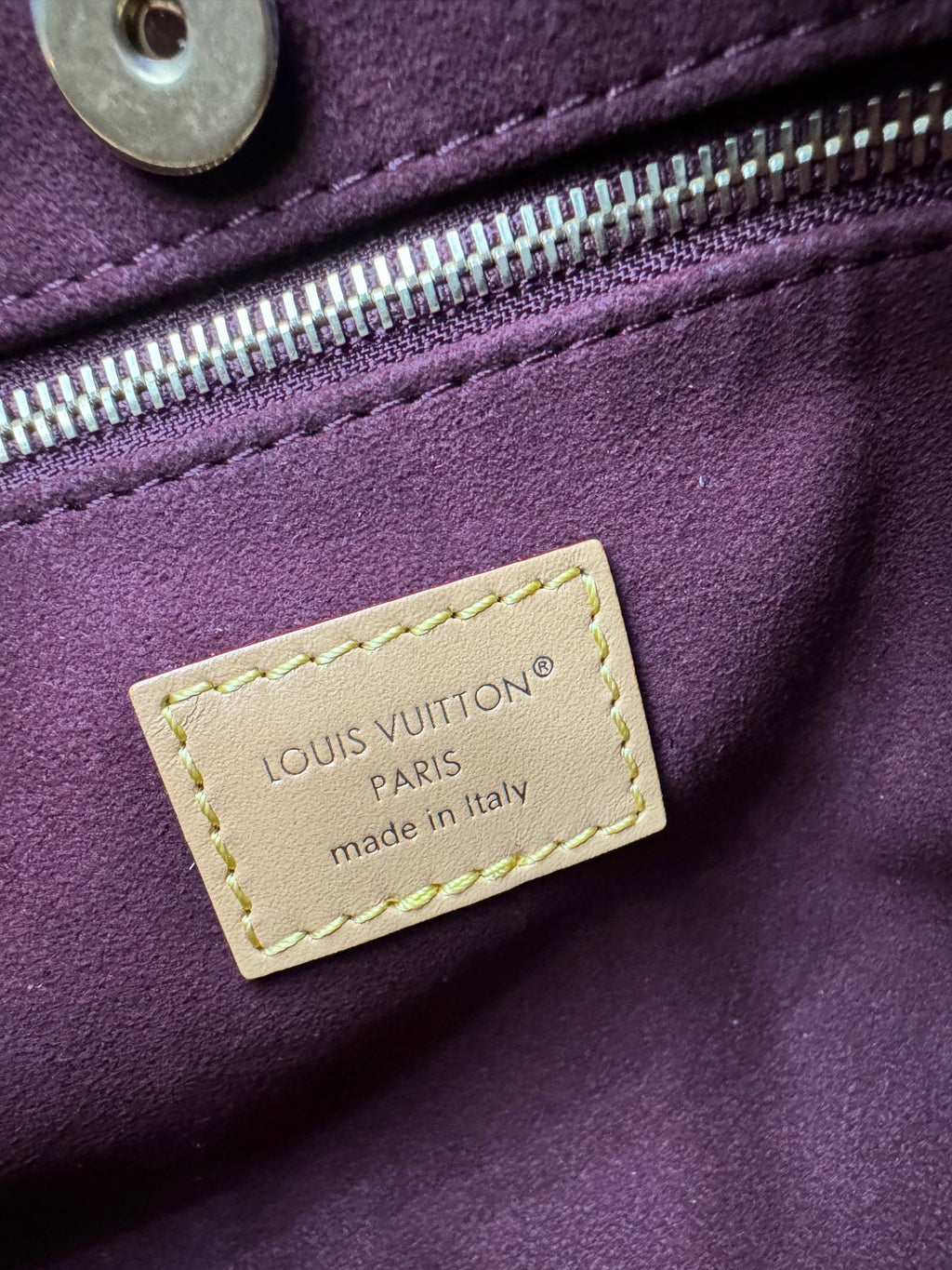 Louis Vuitton purple leather bag exterior with gold zipper and logo label