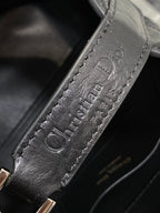 Embossed Dior logo on black leather strap tab