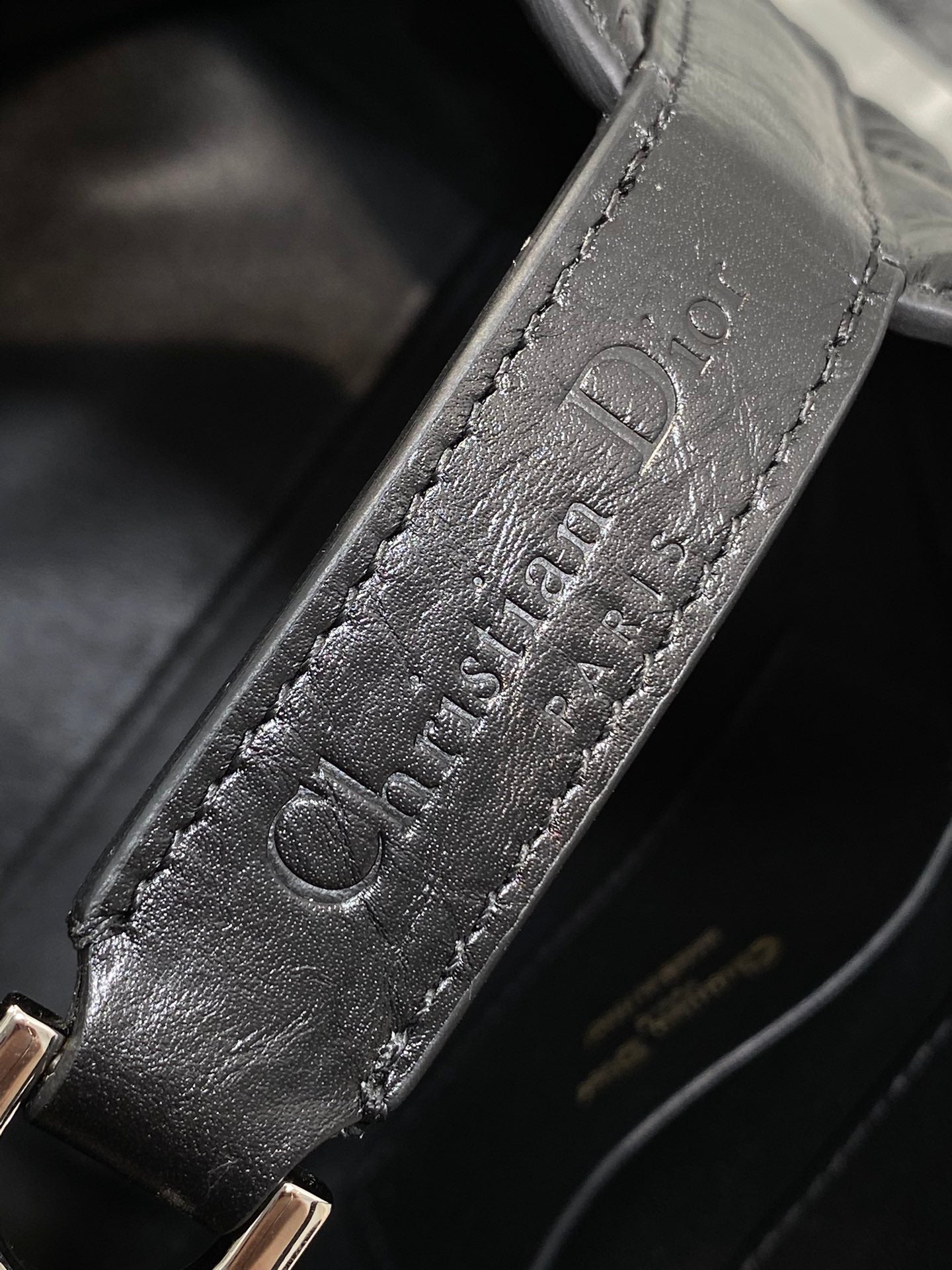 Embossed Dior logo on black leather strap tab