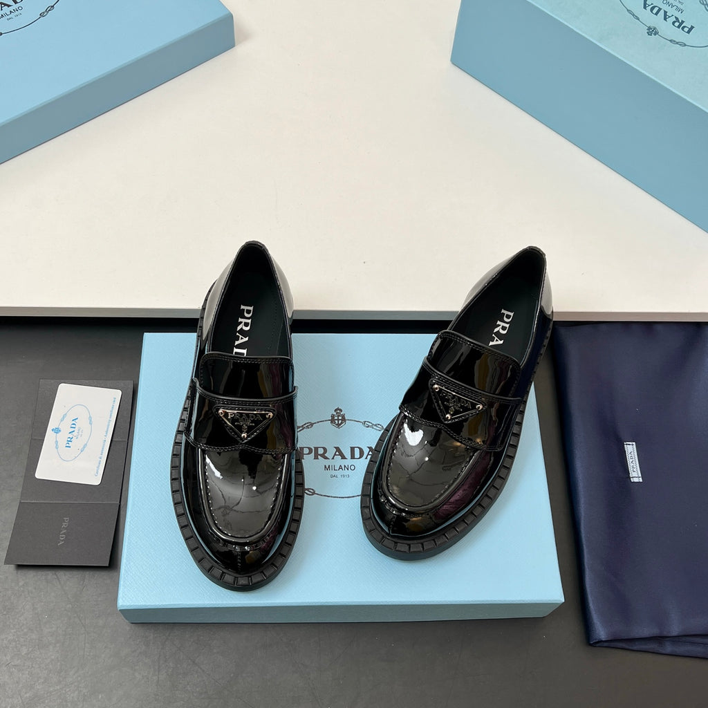 Prada unisex patent loafers, glossy black, side profile with strap detail and tread sole