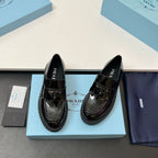 Prada unisex patent loafers, glossy black, side profile with strap detail and tread sole