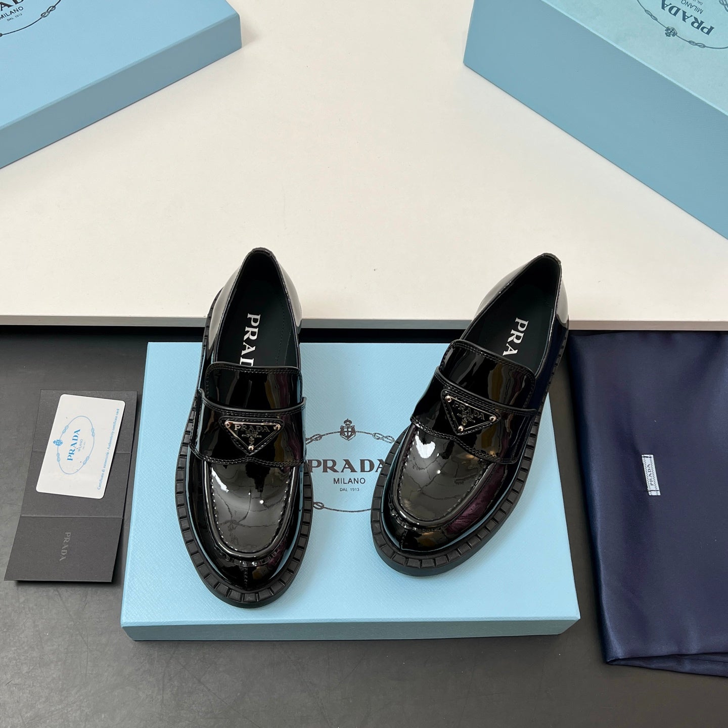 Prada unisex patent loafers, glossy black, side profile with strap detail and tread sole