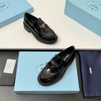 Prada unisex glossy black loafers with buckled strap, gold emblem, and tread sole