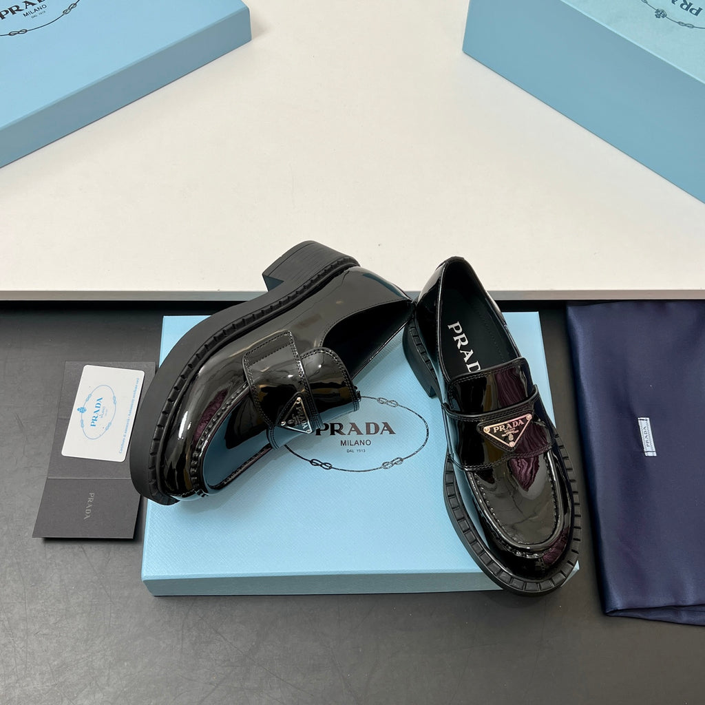 Prada unisex patent loafers, black, side angle with PRADA strap ornament and thick sole