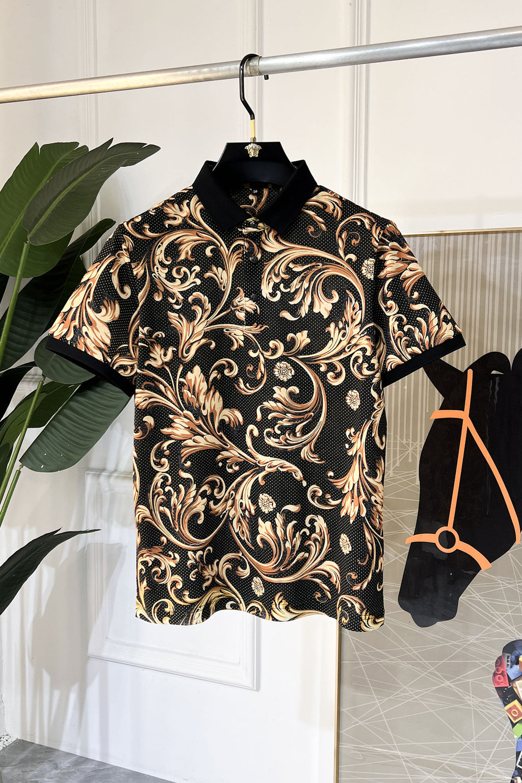 Short-sleeve button-up shirt with ornate baroque print, black base and gold tones, collar.