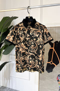 Short-sleeve button-up shirt with ornate baroque print, black base and gold tones, collar.