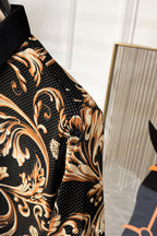 Short-sleeve shirt side view with baroque print on black, gold swirls and short cuff.