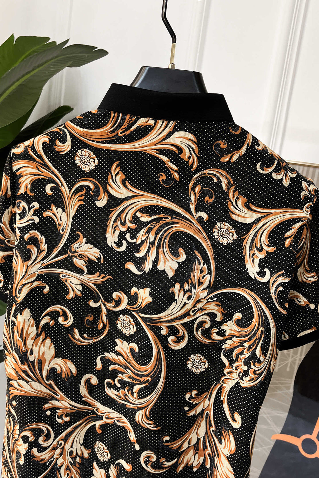 Short-sleeve shirt back view with ornate baroque pattern on black, gold and orange highlights.