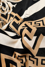 Versace shirt fabric close-up with black, white, and tan Greek key pattern