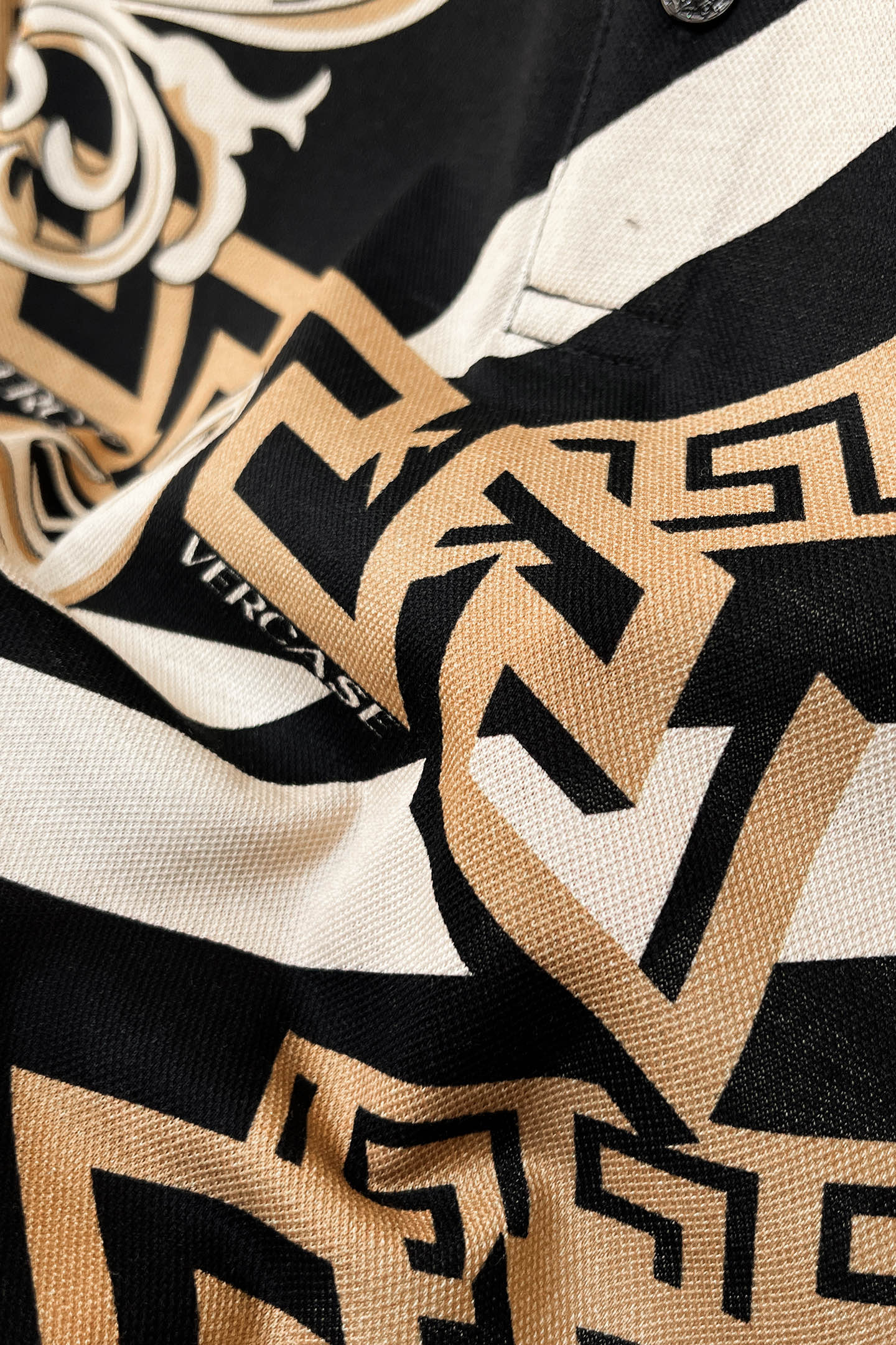 Versace shirt fabric close-up with black, white, and tan Greek key pattern