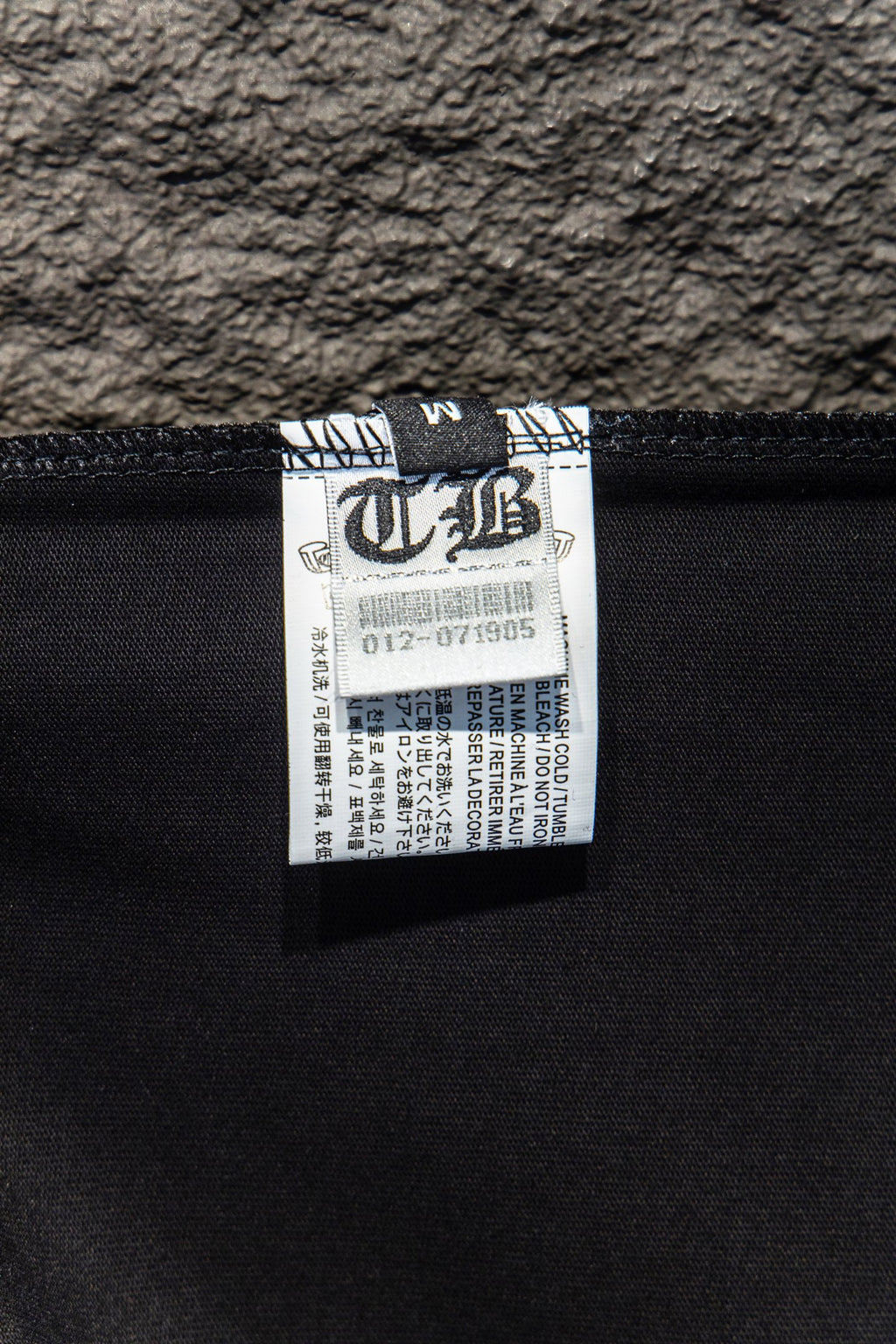 Black T-shirt interior size label tag with barcode and care text