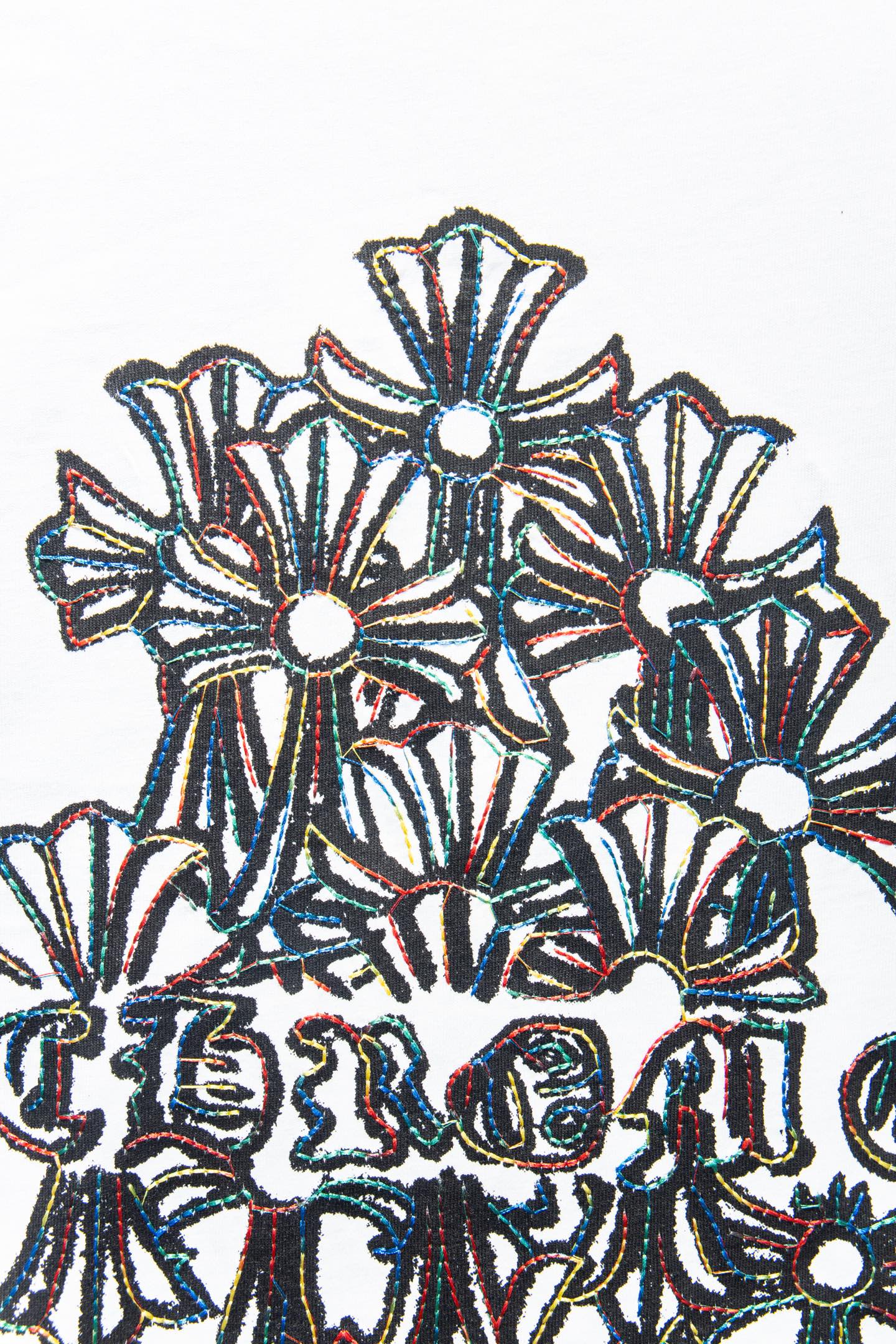 White T-shirt close-up of embroidered floral motifs with dark outline
