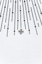 Embellished chest detail with star-shaped cross charm on a white T-shirt