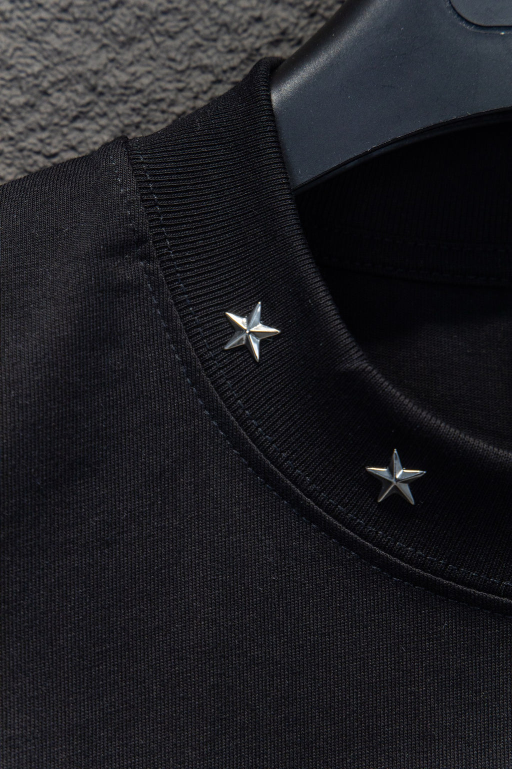 Black T-shirt shoulder seam with two small star appliques near collar