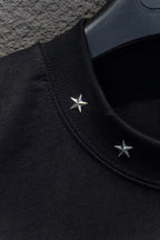 Black T-shirt shoulder seam with two small star appliques near collar
