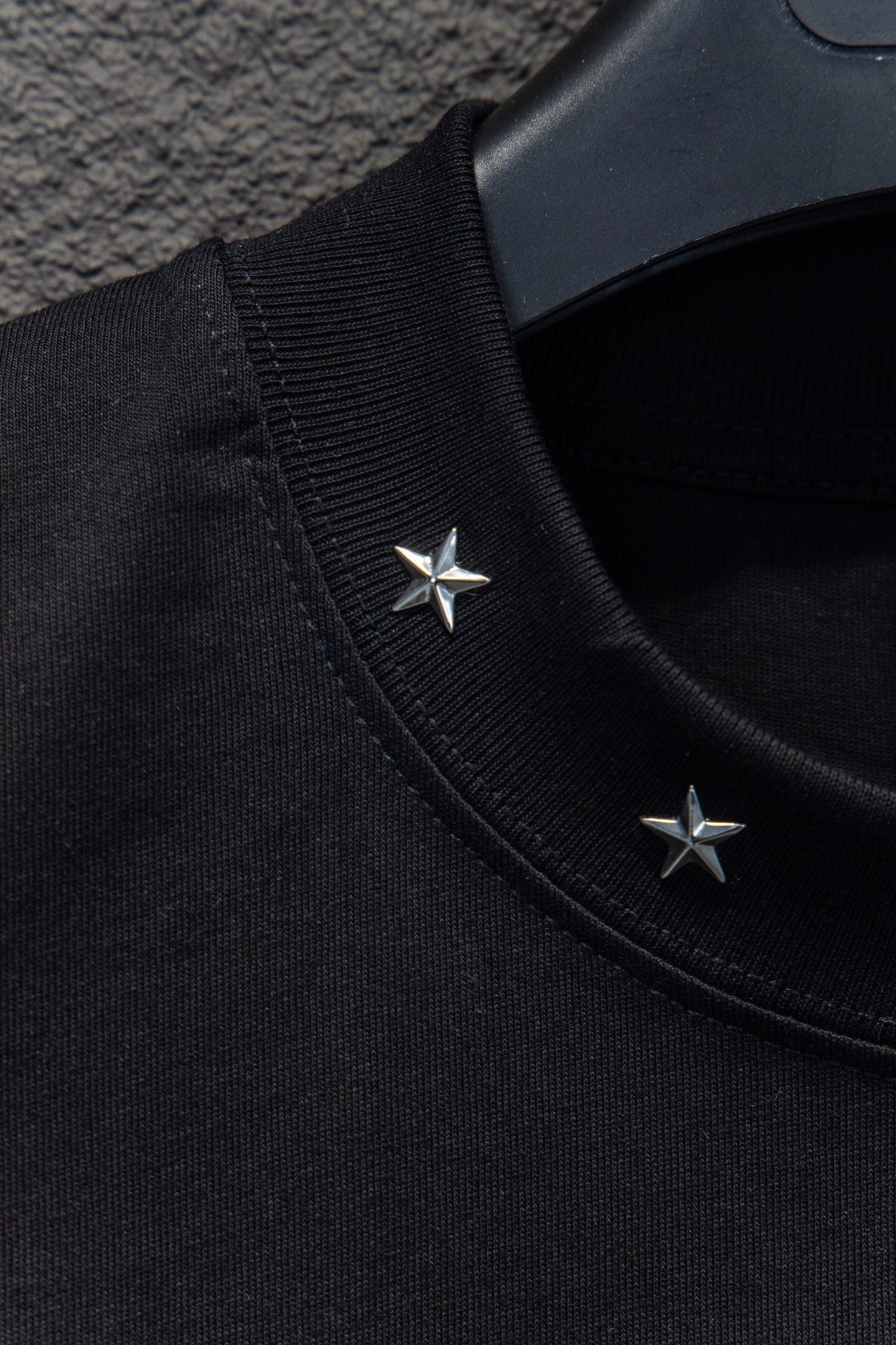 Black T-shirt shoulder seam with two small star appliques near collar