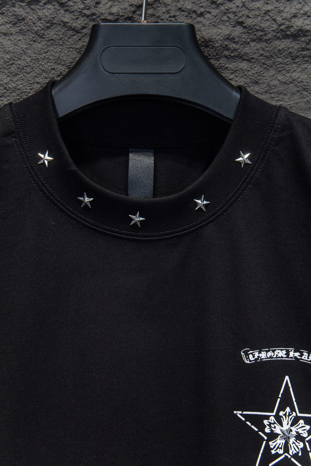 Black T-shirt neckline with star embroidery and partial graphic at chest