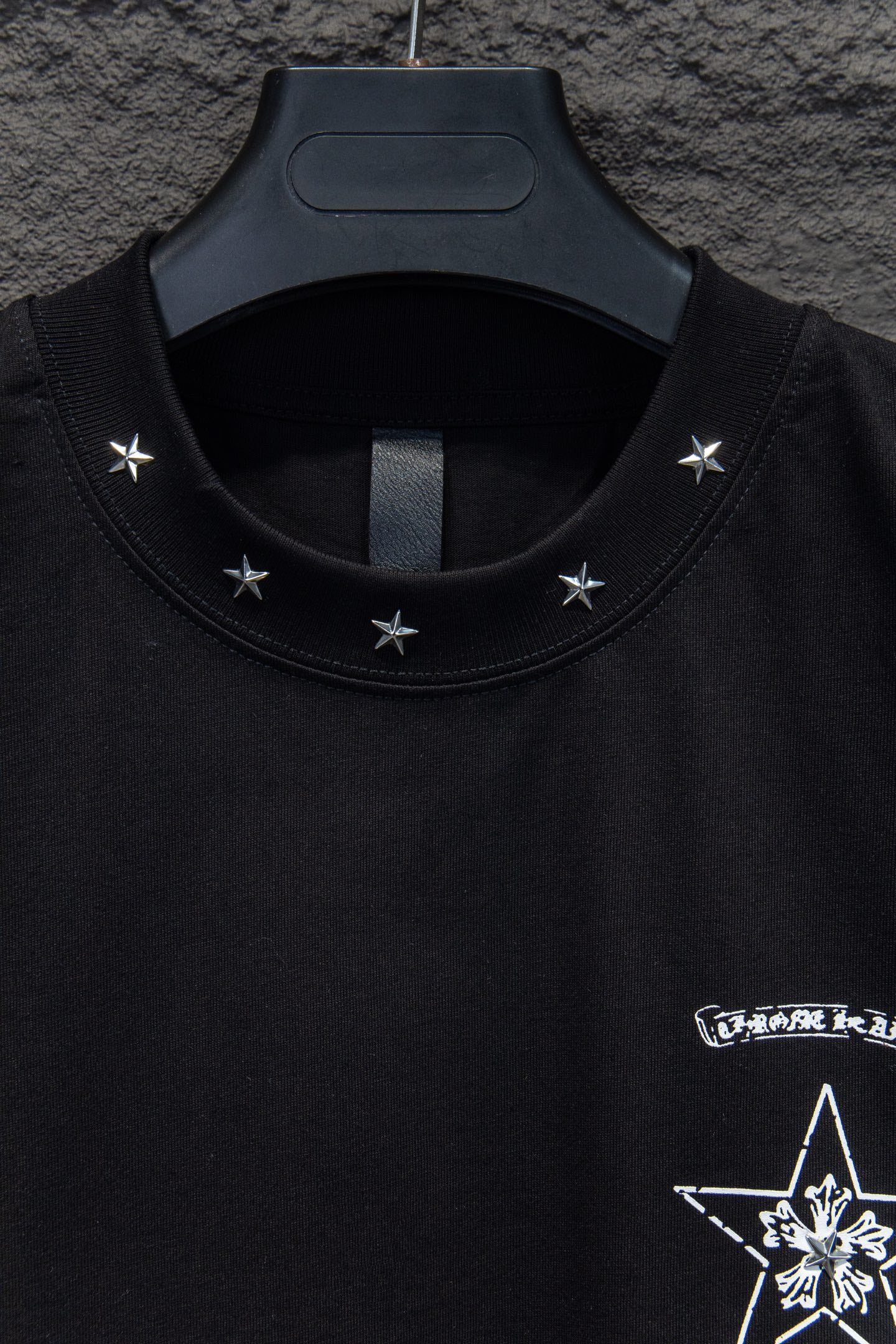 Black T-shirt neckline with star embroidery and partial graphic at chest