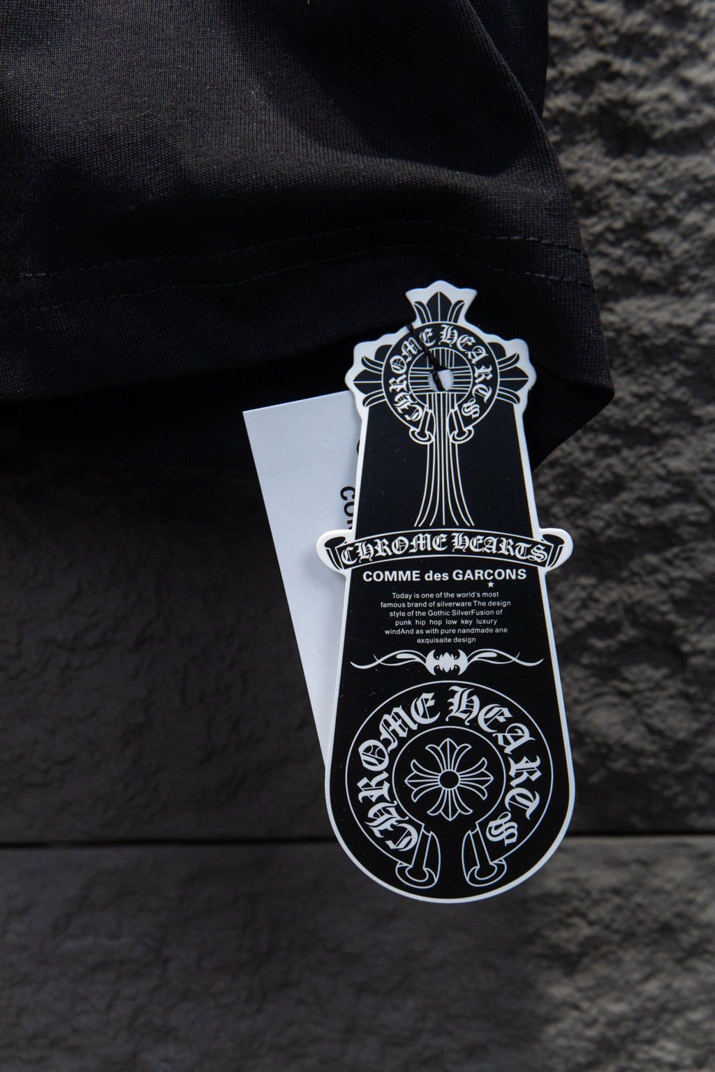 Black T-shirt with hanging white brand tag and black graphic crest
