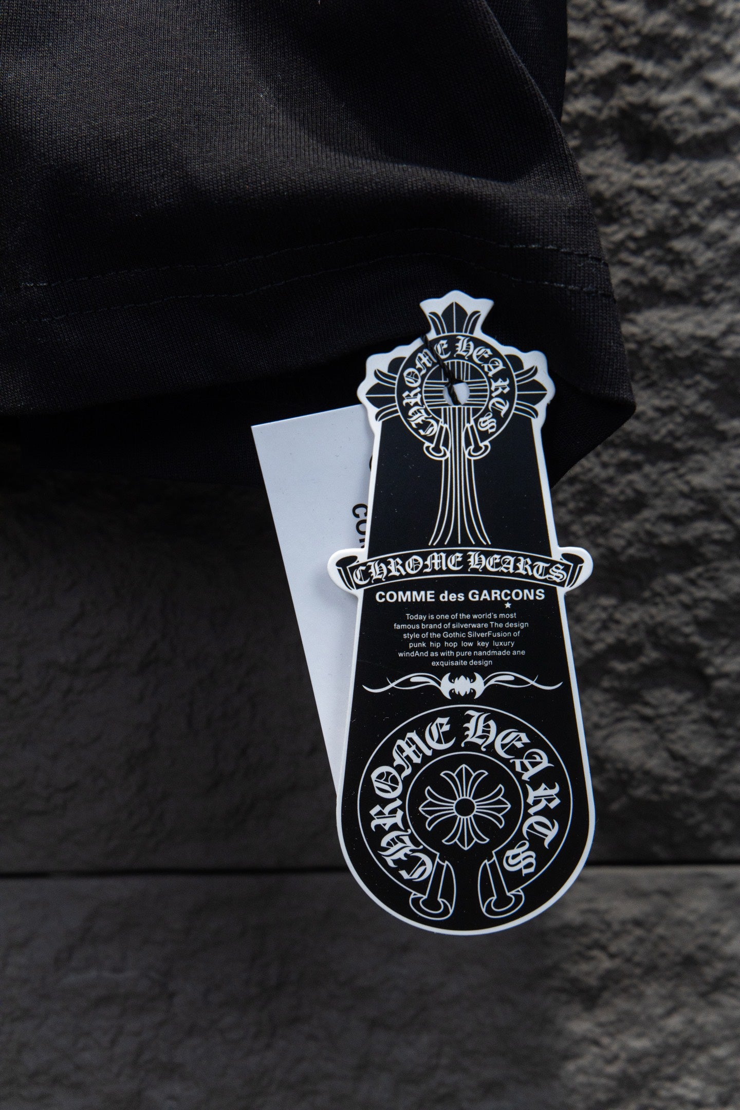 Black T-shirt with hanging white brand tag and black graphic crest